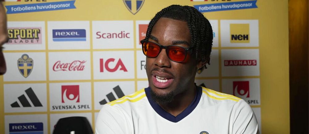 Person i en svensk fotbollströja, framför en sponsorvägg. SVT mikrofon synlig.