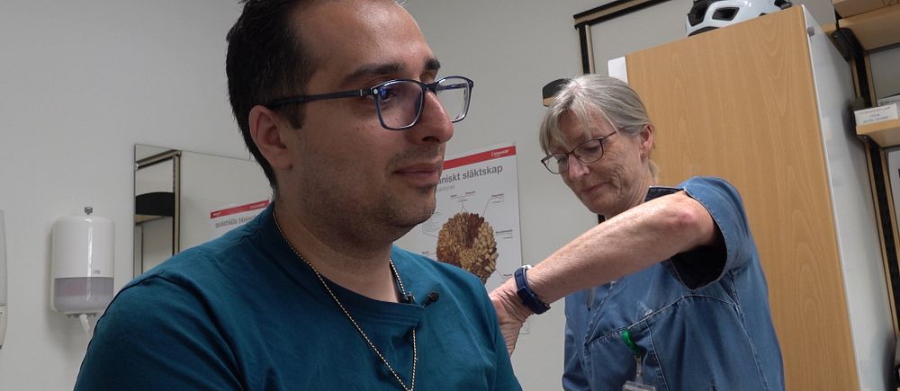 Patient får en spruta i armen av vårdpersonal.