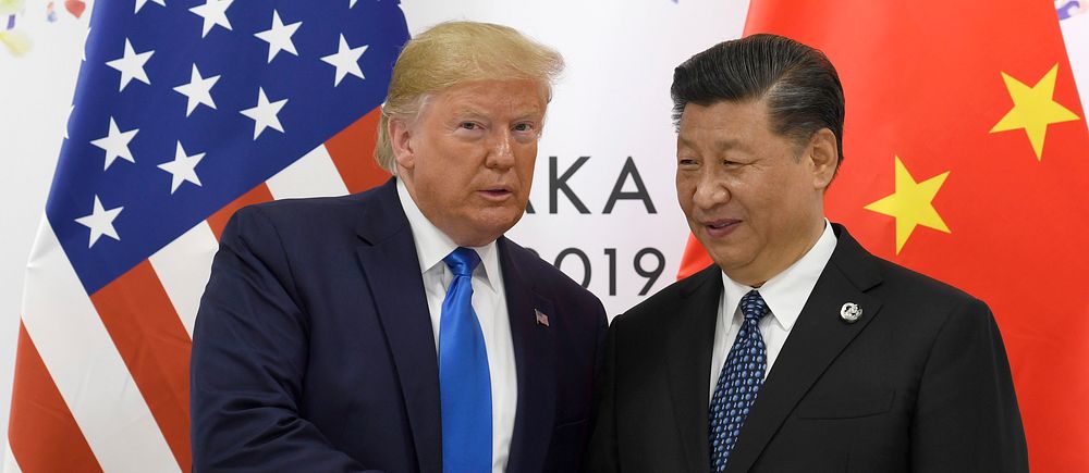 Två statschefer från USA och Kina skakar hand framför sina respektive flaggor.
