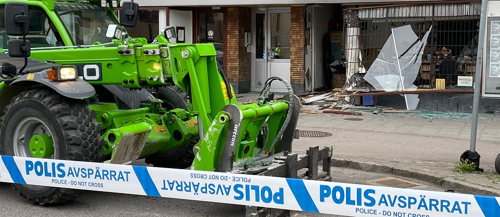 Polisavspärrning vid en trasig butikslokal, grön traktor framför förstörd entré.