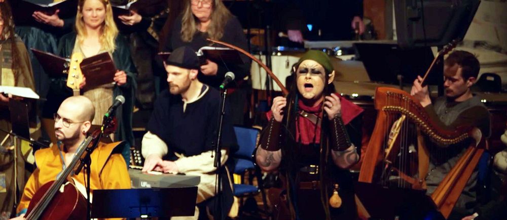 Flera musiker och en sångare uppträder tillsammans på en scen med olika instrument.