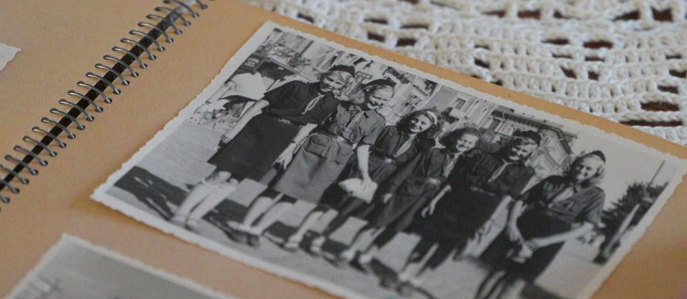 Svartvit foto i album visar en grupp kvinnor som poserar utomhus.