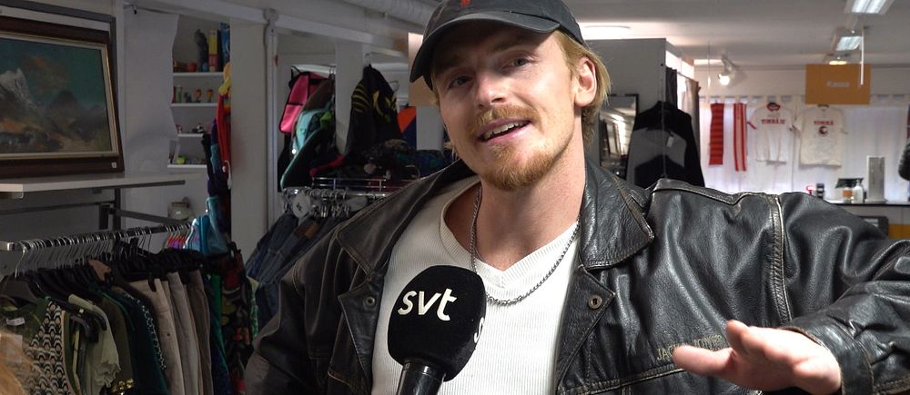 Person i läderjacka i en klädbutik, intervjuas av SVT.