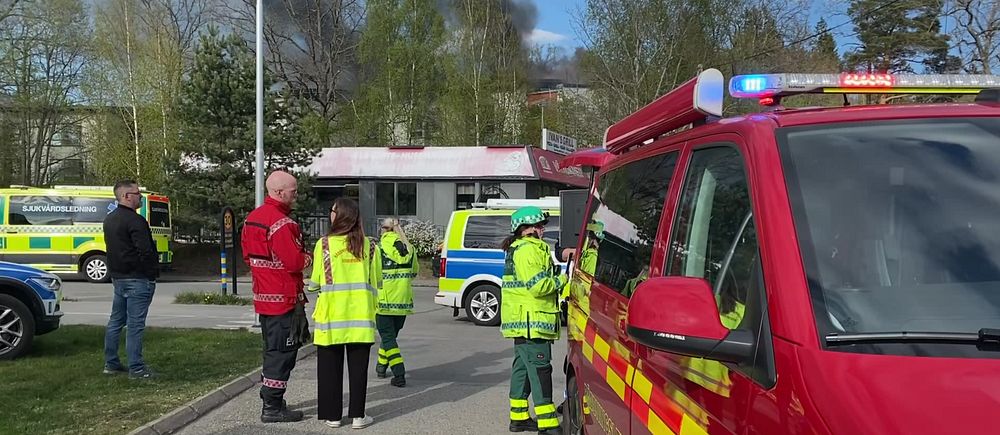 Räddningspersonal och polis arbetar vid avspärrat område med utryckningsfordon.