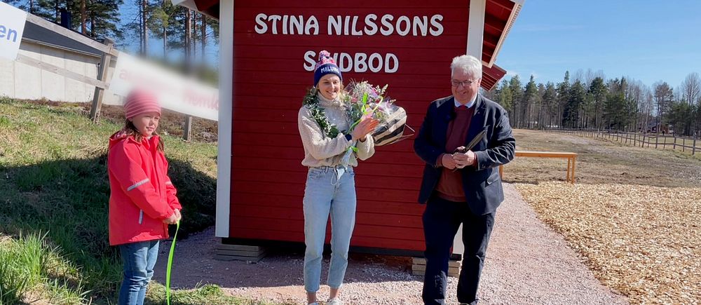 Stina Nilsson står framför sin egna skidbod, och hyllas av politiker och barn, klipper ett band.