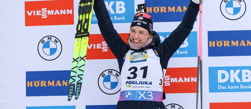 Skidskytten Hanna Öberg sträcker upp armarna i en segergest under prisutdelningen.