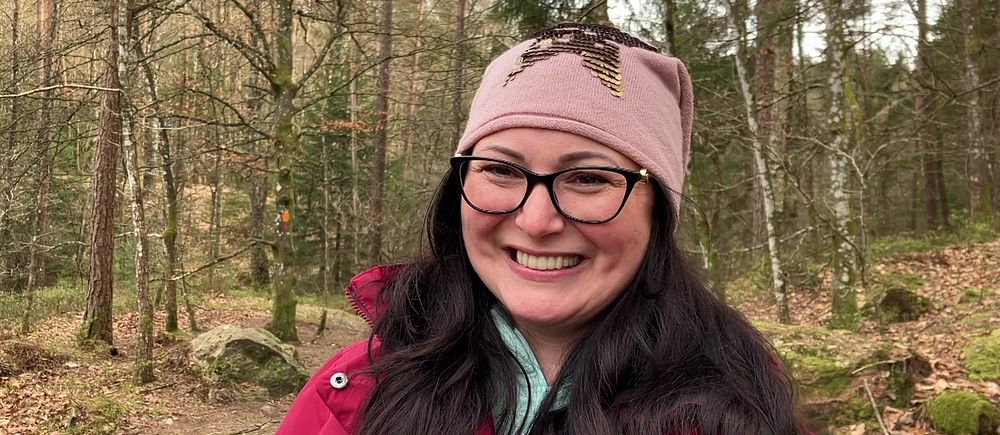 Erika Balogh står i skogen framför några granar vid Danska fallet