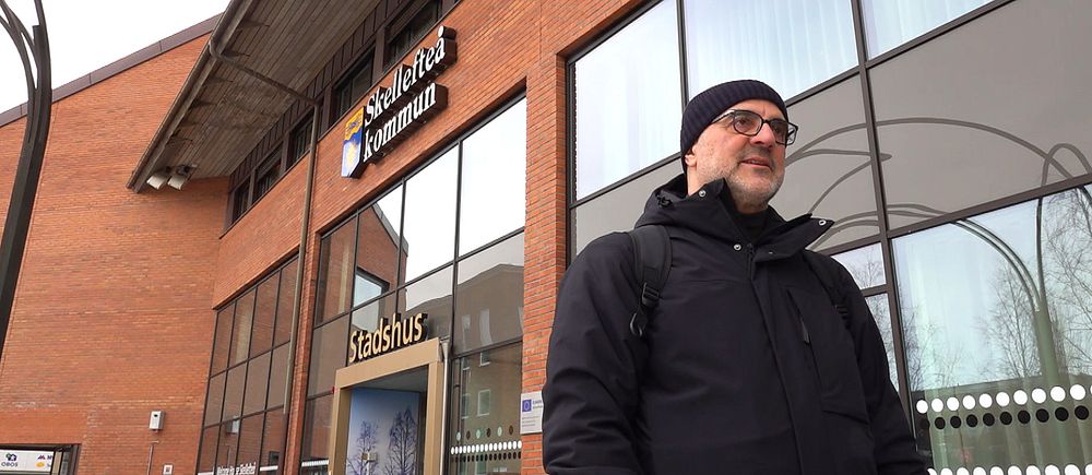 Iosif Karambotis står framför kommunhuset i Skellefteå. Snett bakom honom syns kommunens logga och texten ”Skellefteå kommun”.
