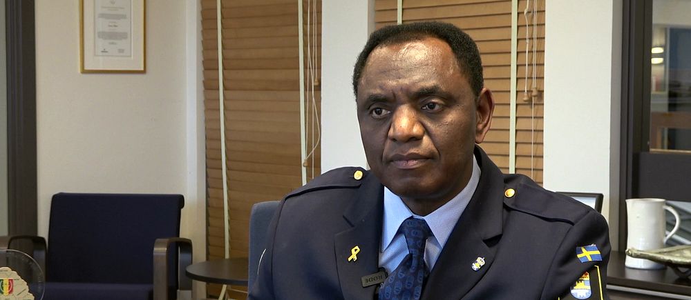 Jacques Mwepu sitter i uniform i kontorsmiljö med möbler och inredning i bakgrunden.