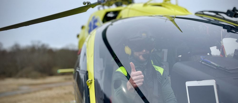 Helikopterpilot gör tummen upp i ambulanshelikoptern.