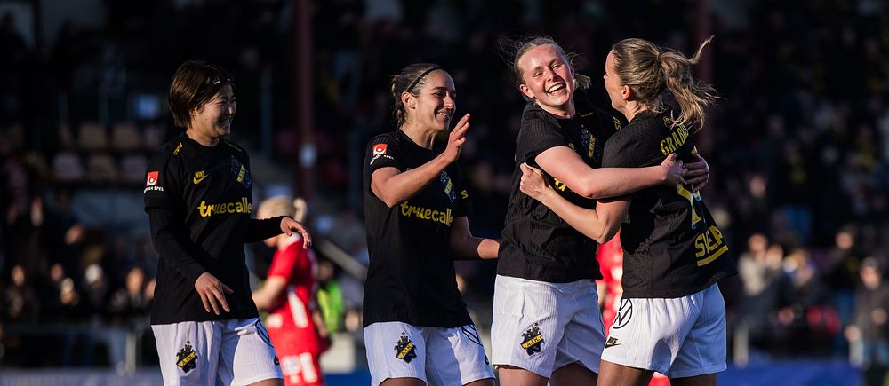 Tre spelare i svarta t-shirts jublar efter mål