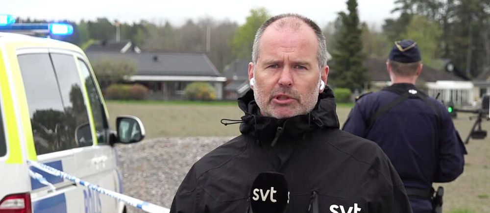 Reporter från SVT rapporterar framför polisbil och avspärrning vid en utryckning.