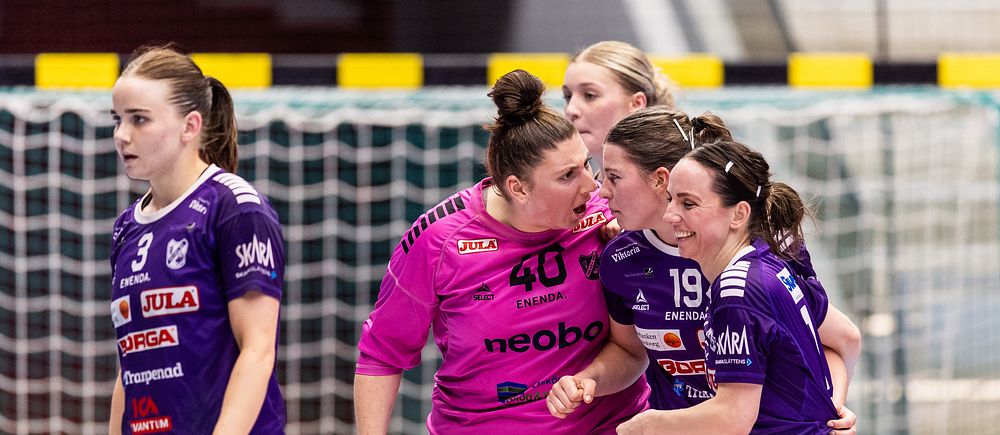 Fyra handbollsspelare samlas vid målet under en match i en inomhushall.