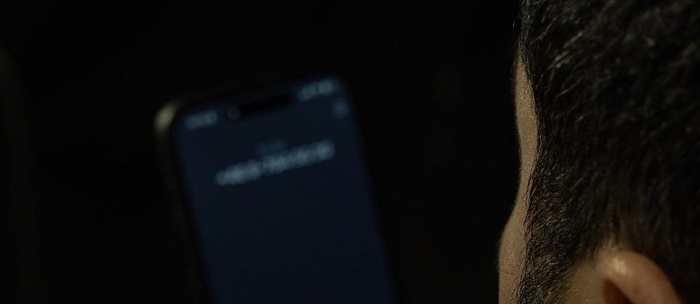 Person håller i smartphone med oidentifierat nummer på skärmen.