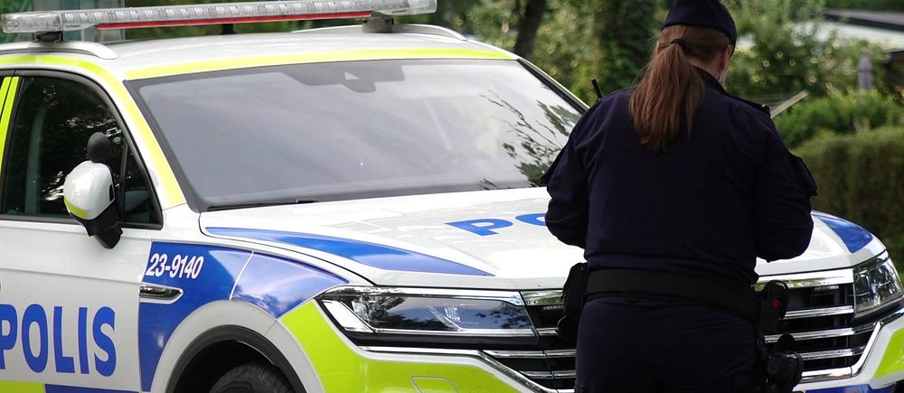Kvinnlig polis framför polisbil