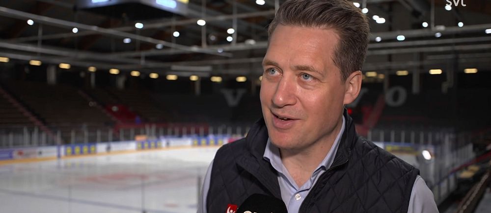 Person intervjuas i en nästan tom hockeyarena. SVT-mikrofon synlig.