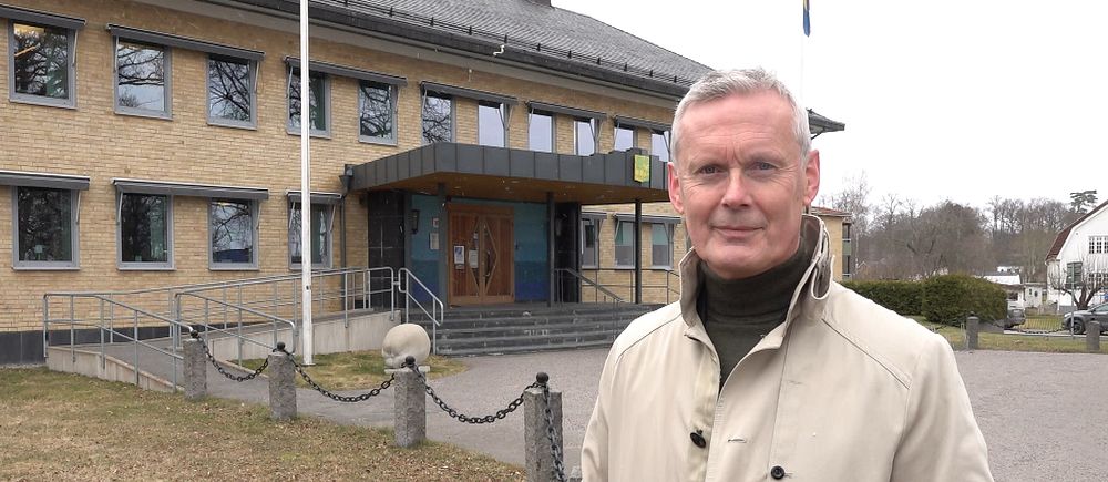 Person vid byggnad med gult tegel, parkmiljö runtom.