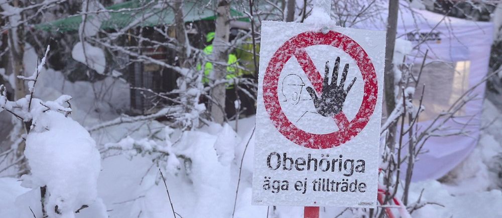 Varningsskylt om tillträdesförbud står i ett snötäckt skogsområde.