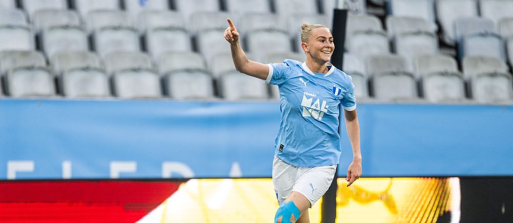 Fotbollsspelare i ljusblått firar ett mål på en nästan tom arena.