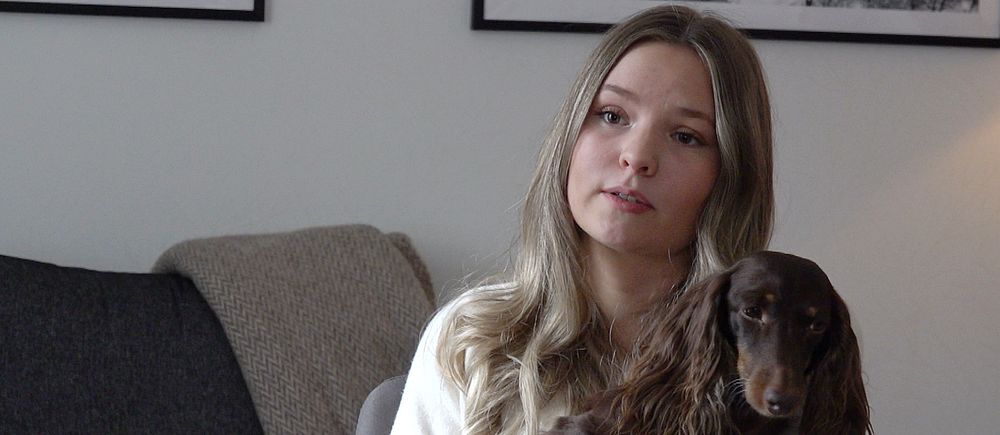 Emilia Nilsson, matte till dvärgtaxen Cooper. håller sin hund i famnen.