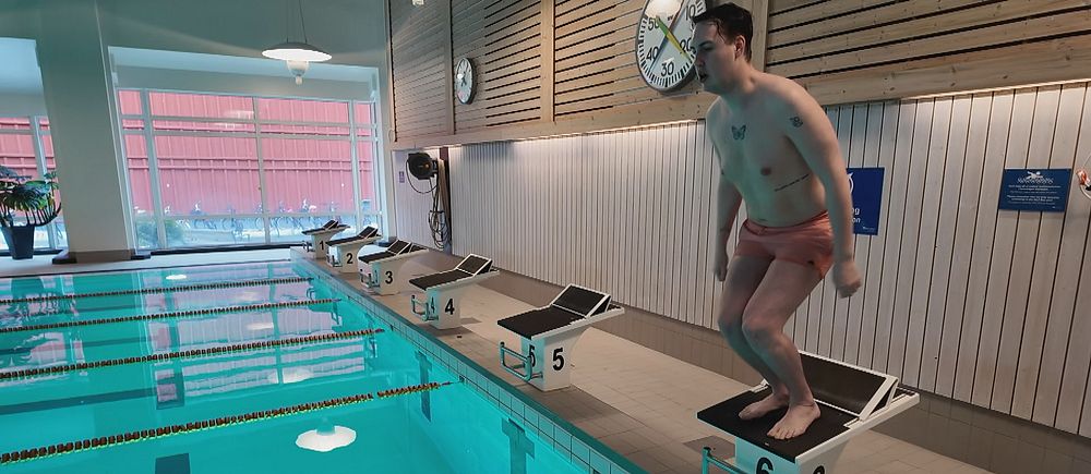 Christoffer Johansson förbereder hopp från startblock vid en simbassäng.