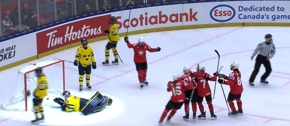 Kanadenskt hockeylag firar mål mot Sverige, svensk målvakt ligger på isen.