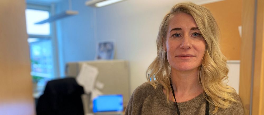 En kvinna med blont hår och grå tröja.