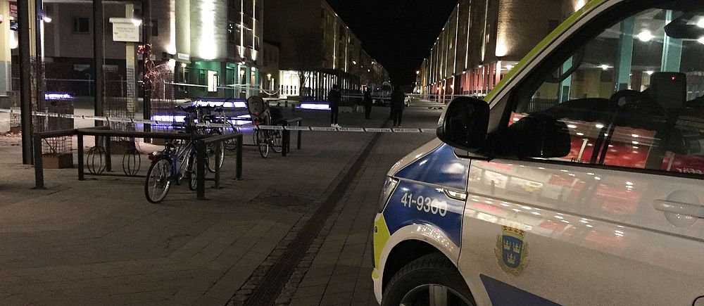Polisbil och avspärrningar på en nattlig gata i stadsmiljö.
