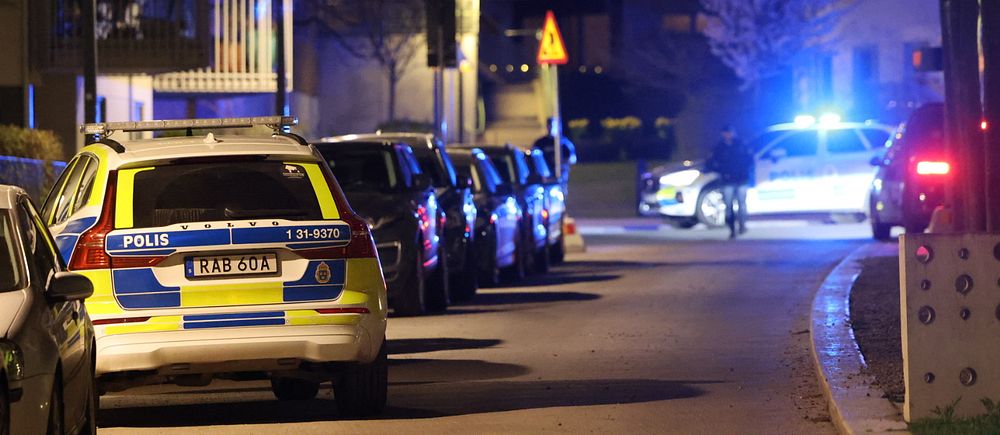 Polisbilar på plats längs en gata i ett bostadsområde i Södra Hammarbyhamnen efter fredagkvällens skottlossning.