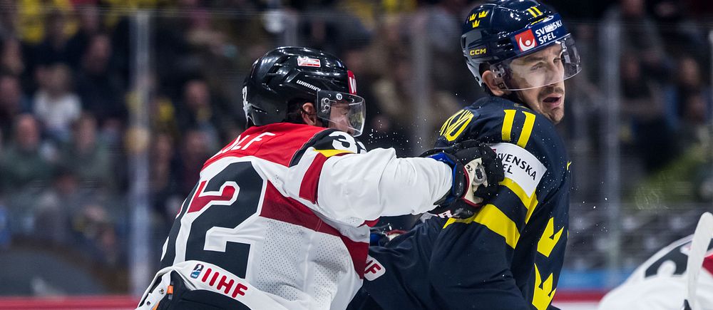Kanadensisk ishockeyspelare tacklar svensk spelare under match.