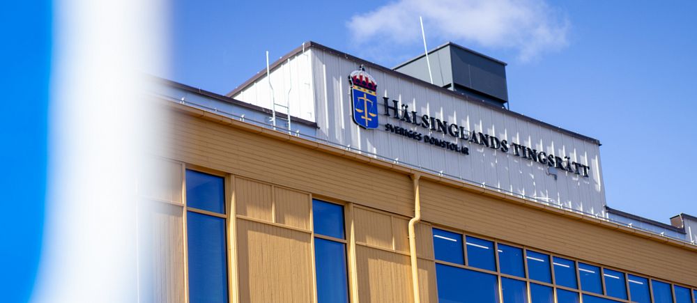 Fasad på Hälsinglands tingsrätt under klarblå himmel.