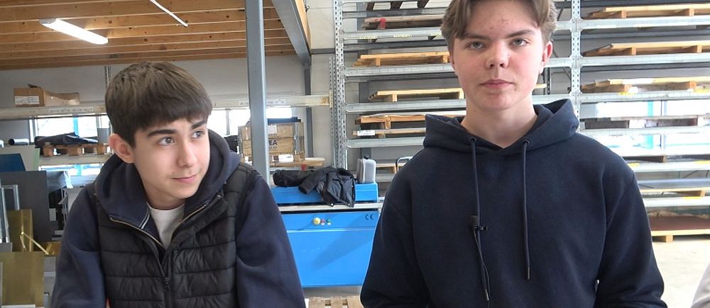 Två personer i en verkstad håller små föremål.