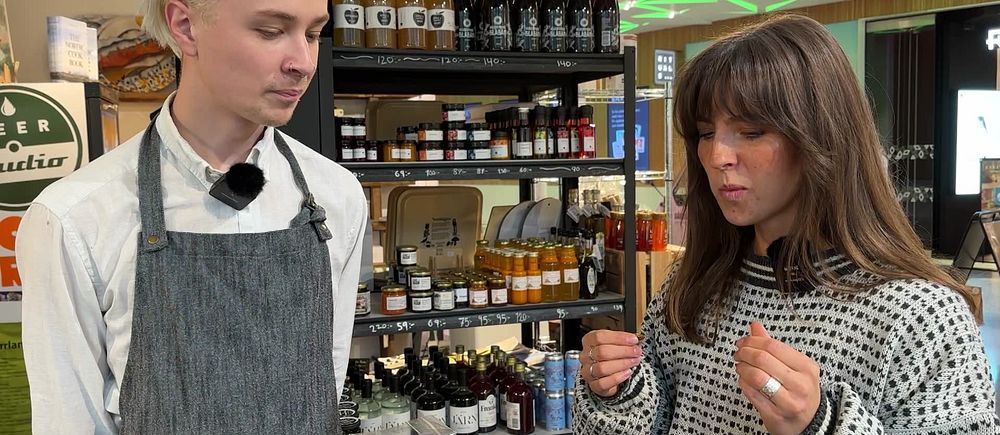 Reporter Linnea Vennström står bredvid ett butiksbiträde och smakar på fröknäcke med syrsor i på en butik i Umeå.