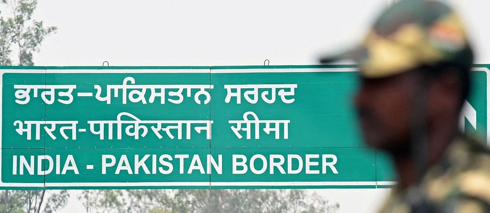 Vägskylt med texten ”India-Pakistan Border” på tre språk och en soldat i förgrunden.