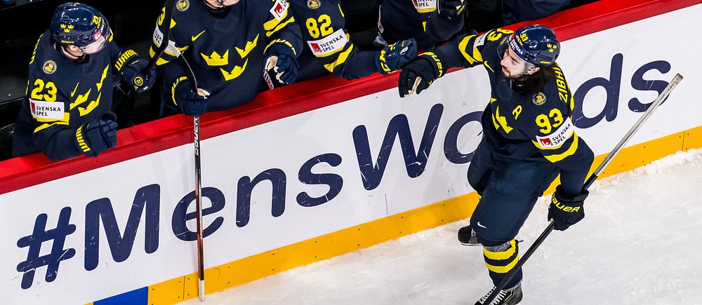 En svensk ishockeyspelare firar med lagkamrater vid sargen under en match.