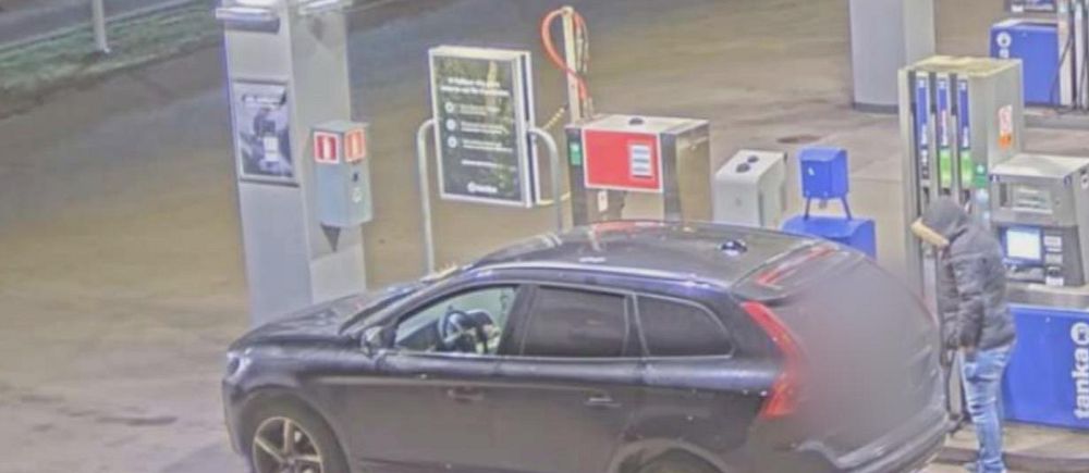 Mörk personbil vid bensinpump på obemannad bensinstation kvällstid.