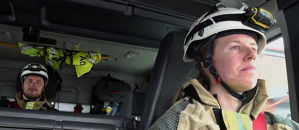 Brandmän i utryckningsfordon iförda hjälmar och skyddskläder.