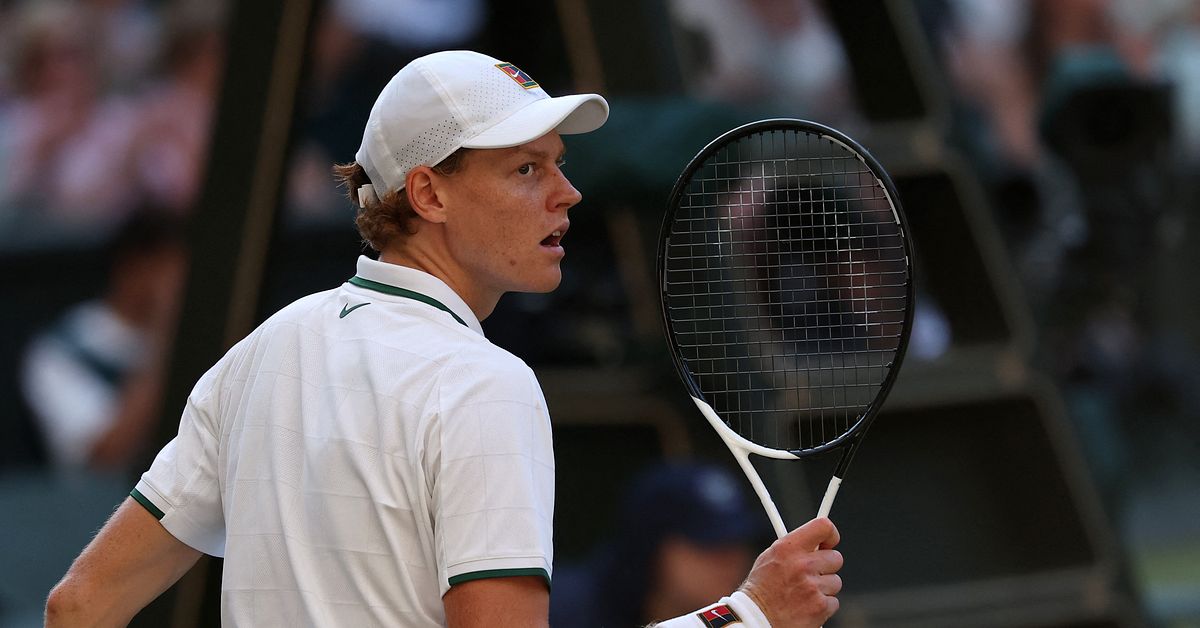 Jannik Sinner i vit tennisklädsel under en match, med racket i handen