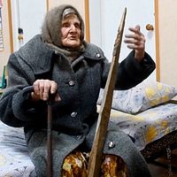 Lidia Stepanivna Lomikovska sitter på en säng i Ukraina efter att ha flytt ryska anfall