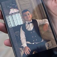 T.v. bild på en telefon som visar en bild av en finklädd pojke. T.h. pojke som tittar åt sidan.