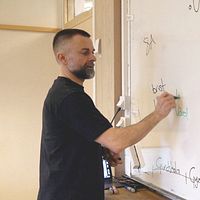 En man skriver med en tuschpenna på en whiteboard.