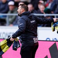 Tvådelad bild. Vänster: tränare på fotbollsplan. Höger: röd tröja ligger på gräset.