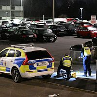 Delad bild. Till vänster: polis arbetar vid patrullbil på parkering. Till höger: reporter med mikrofon.