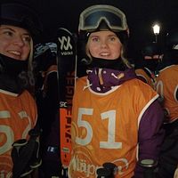 Tre kvinnor med skidor och nummerlappar på sig