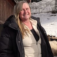 En kvinna ler framför flera får i Naggen i Ånge.