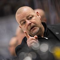 Två personer i svarta kläder diskuterar vid en sportevenemang.