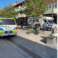 Två polisbilar som står på en gågata i centrala Sandviken. Två poliser står och pratar med kvinnor.