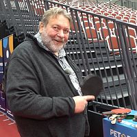 Torsten Jansson vid tom läktare håller pingisracket framför bord med fler rackets.