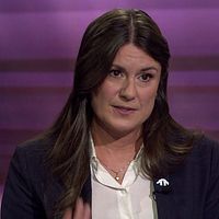 Två personer samtalar i en tv-studio med lila bakgrund.