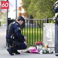 Två poliser vid ett blomhav på trottoaren, minnesplats efter händelse utomhus.
